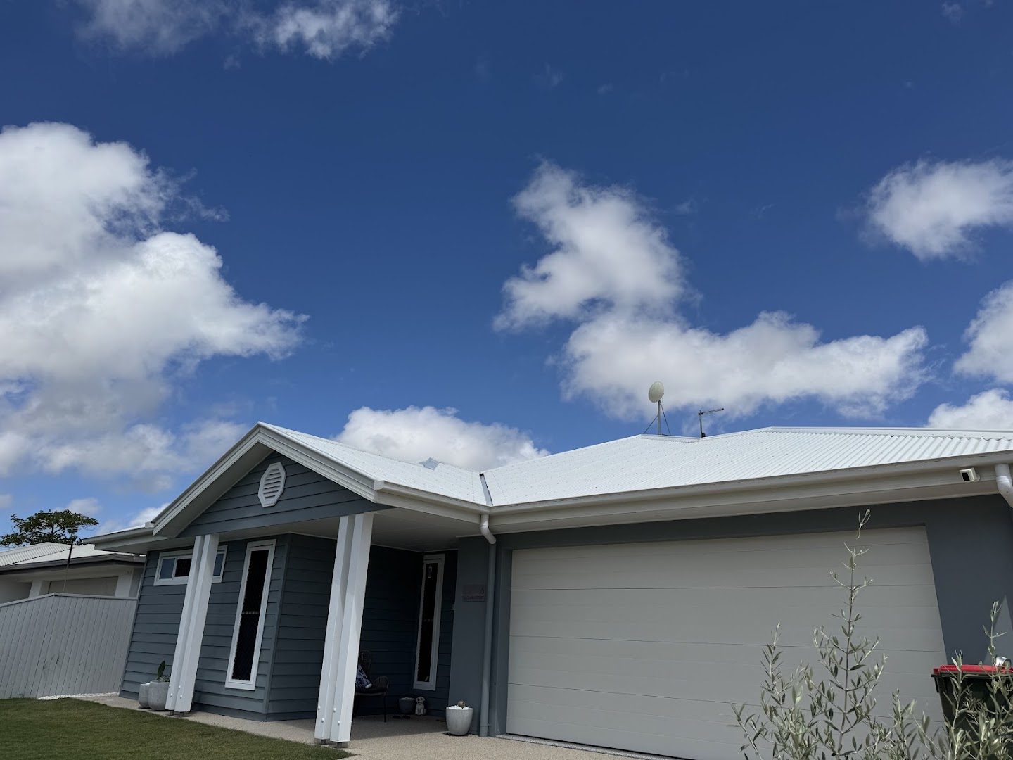 A modern low-set home with a metal roof under a bright blue sky