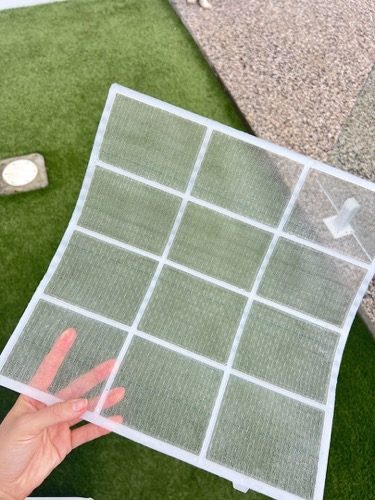 An air conditioner filter held up to the light