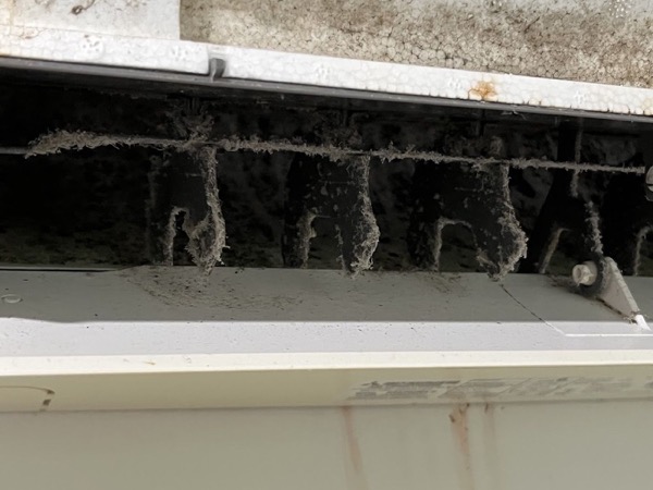 A close view along the inside of an air conditioner head showing heavy build-up