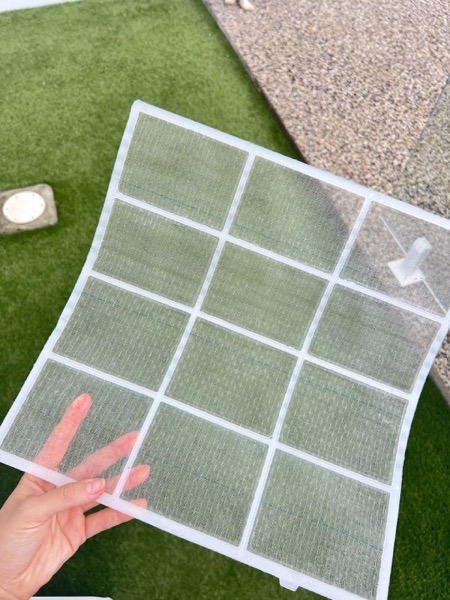 An air conditioner filter held up against the light