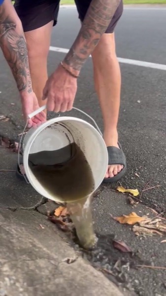 Dirty water being tipped out of a bucket at the kerb