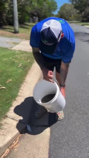 A worker in a branded cap carrying a bucket back to the vehicle