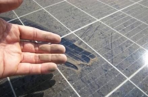 A hand resting on a solar panel showing the film across the glass